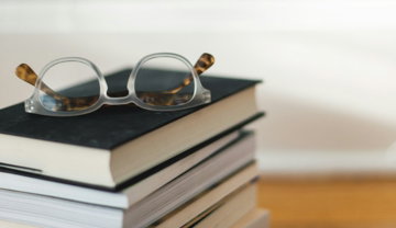 clear-framed-eyeglasses-on-top-of-pile-of-books.jpg clear framed eyeglasses on top of pile of books